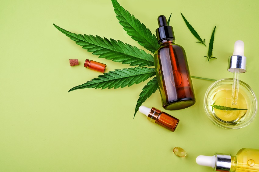 Glass bottles with CBD oil, THC tincture and hemp leaves on a yellow background. Flat lay, minimalism. Cosmetics CBD hemp oil. Different glass bottles with CBD OIL