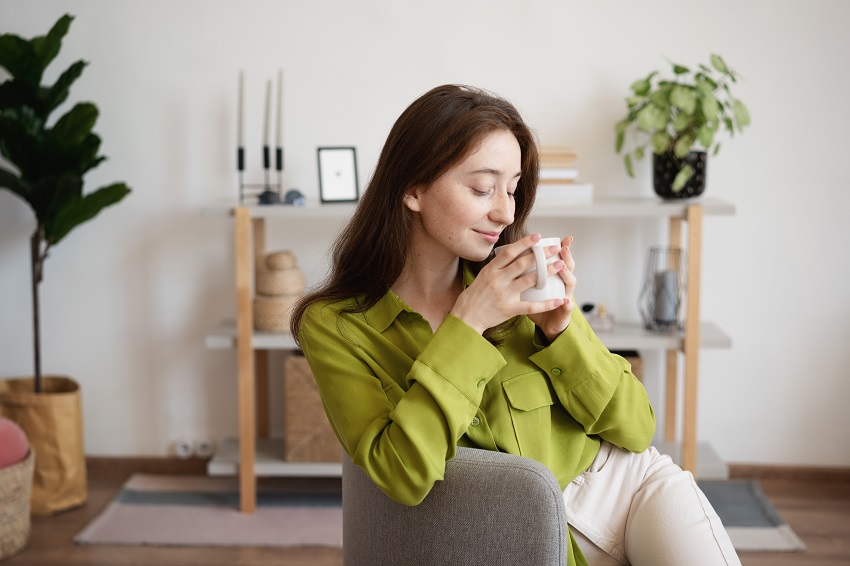 Young beautiful smiling woman in a green blouse with a mug of co Lady drinking coffee