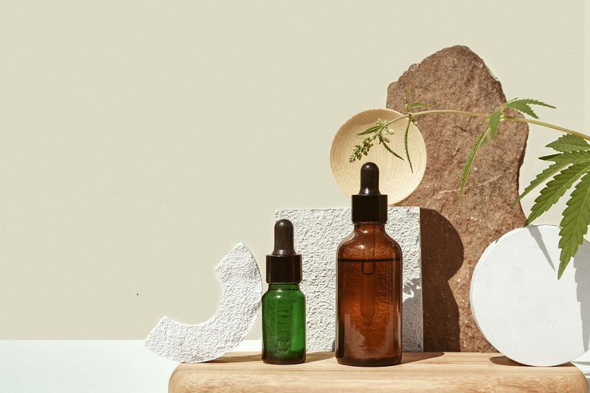 Various glass bottles with CBD oil, THC tincture and hemp leaves on beige background. minimalism Oil bottles
