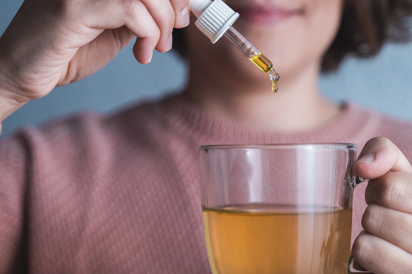 Cbd hemp oil - Woman pouring cannabis oil inside drink tea cup - Anxiety alternative treatment - Focus on dropper Cbd hemp oil - Woman pouring cannabis oil inside drink tea cup - Anxiety alternative treatment - Focus on dropper